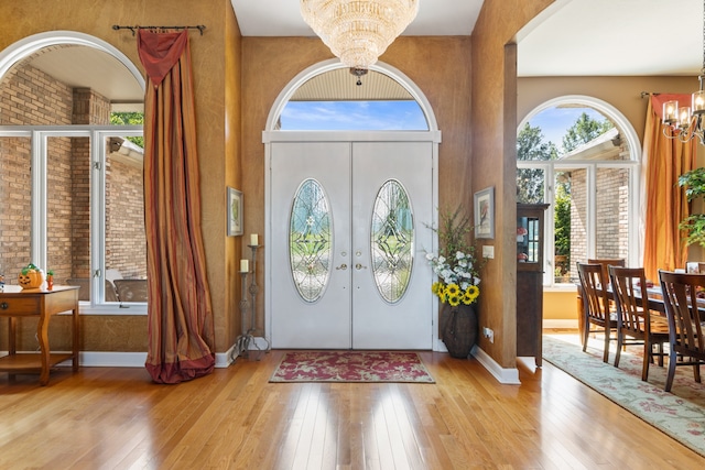 foyer entrance featuring hardwood / wood-style flooring, a chandelier, and french doors