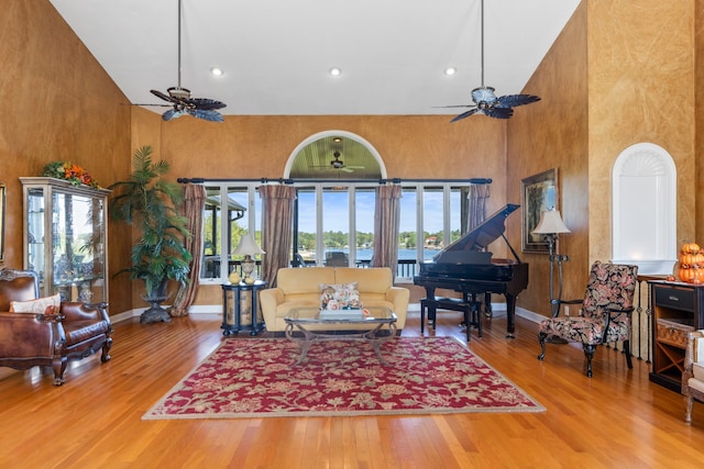 living room featuring ceiling fan, hardwood / wood-style flooring, and a towering ceiling