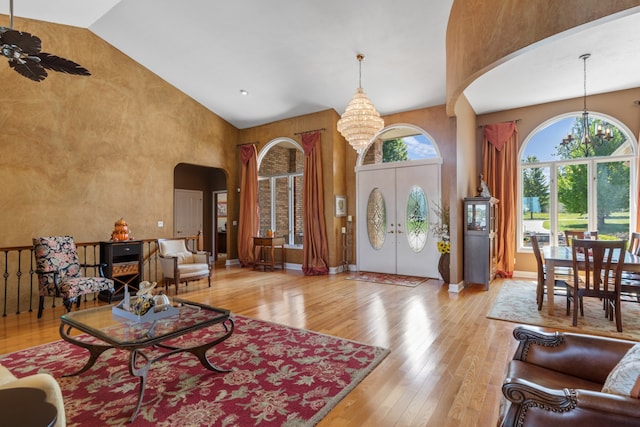 foyer entrance featuring ceiling fan with notable chandelier, high vaulted ceiling, and light hardwood / wood-style flooring