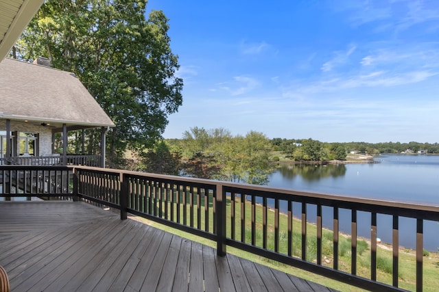 deck with a water view, a lawn, and ceiling fan