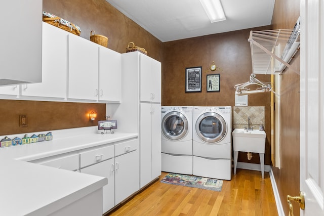 laundry room with light hardwood / wood-style flooring, cabinets, and washer and dryer