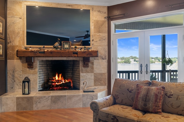 living room featuring a tiled fireplace, vaulted ceiling, wood-type flooring, ceiling fan, and ornamental molding