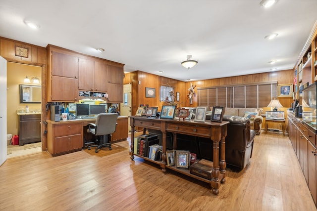 living room with wood walls, built in desk, and light hardwood / wood-style flooring
