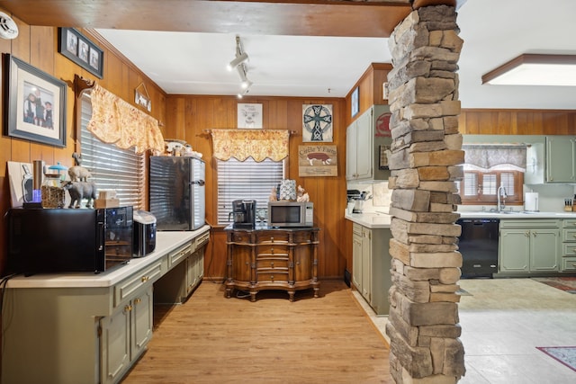 kitchen with green cabinets, light hardwood / wood-style flooring, ornate columns, black appliances, and wood walls
