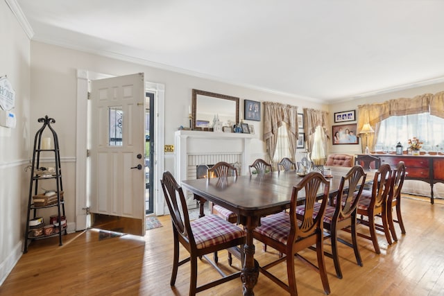dining space with ornamental molding, plenty of natural light, hardwood / wood-style flooring, and a brick fireplace