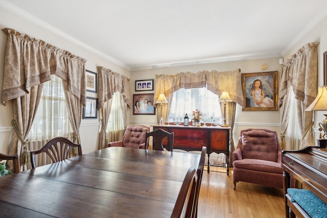 dining space with light wood-type flooring, crown molding, and a wealth of natural light
