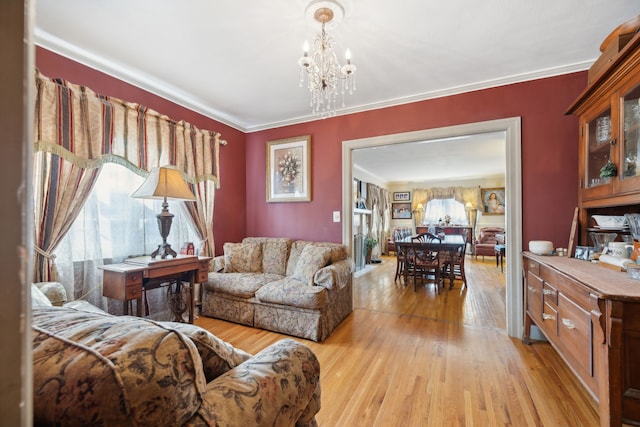 living room featuring ornamental molding, an inviting chandelier, and light hardwood / wood-style floors