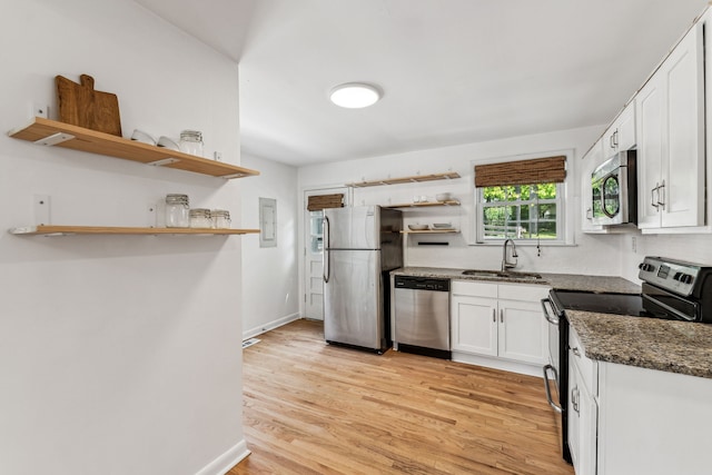 kitchen with light hardwood / wood-style floors, stainless steel appliances, sink, white cabinetry, and dark stone countertops