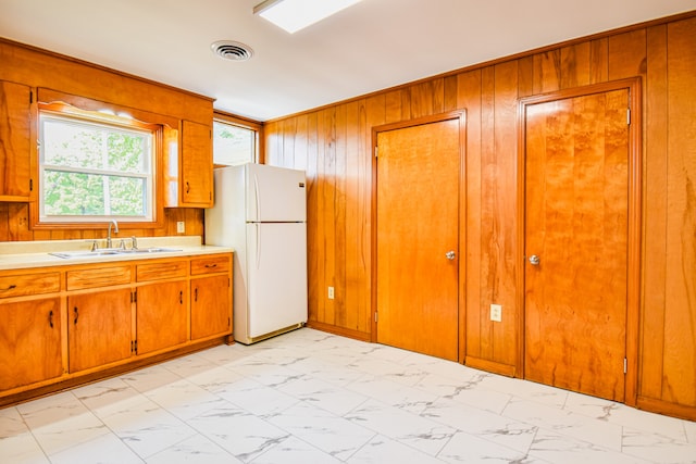 kitchen featuring sink, white refrigerator, and wooden walls