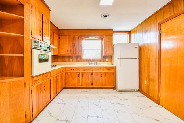 kitchen featuring white appliances, sink, and wooden walls