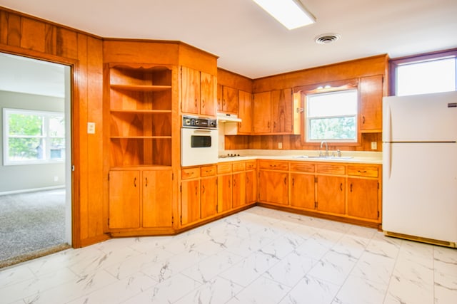 kitchen with white appliances, a healthy amount of sunlight, sink, and light colored carpet