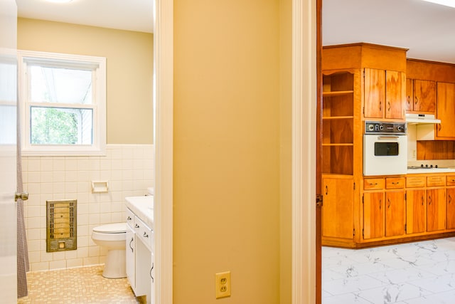 bathroom with vanity, toilet, and tile walls