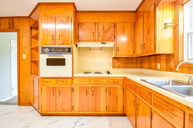 kitchen featuring white appliances, wooden walls, and sink