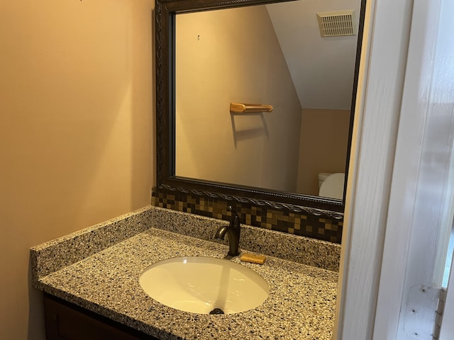 bathroom featuring vanity, tasteful backsplash, and toilet