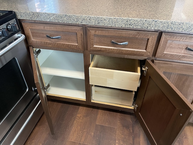 details with light stone counters, stainless steel stove, and dark hardwood / wood-style flooring