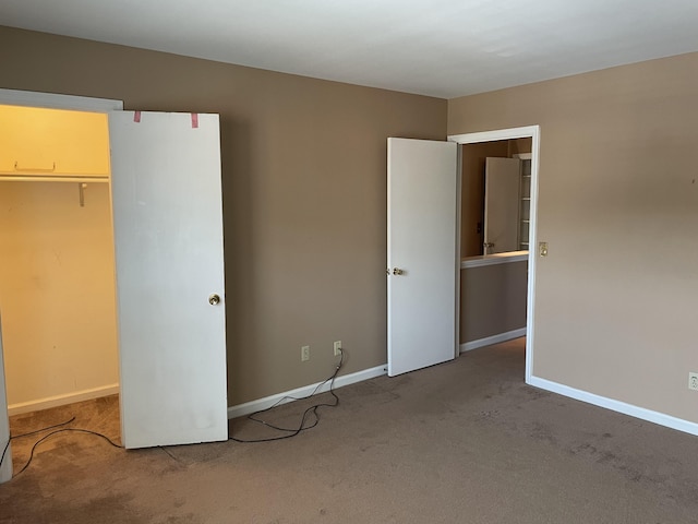 unfurnished bedroom with carpet flooring, a closet, and a spacious closet