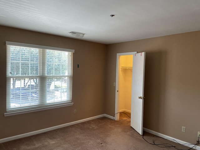 unfurnished bedroom featuring a closet, carpet flooring, and a spacious closet