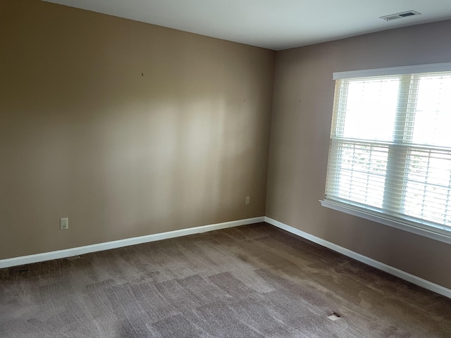 empty room featuring plenty of natural light and dark carpet