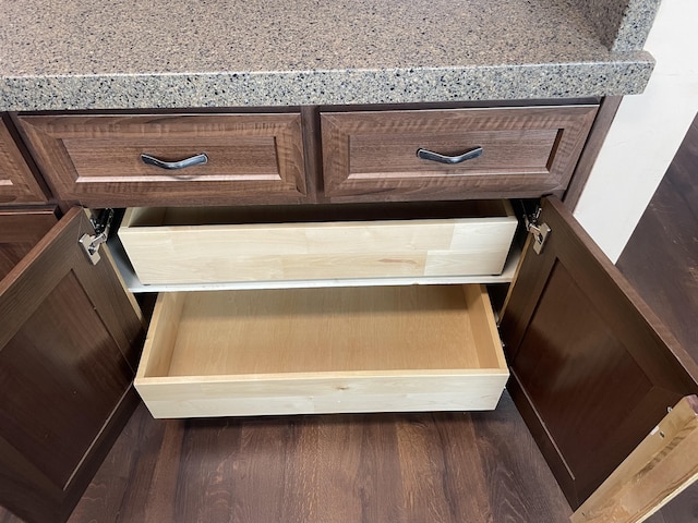 interior details featuring dark wood-type flooring, dark brown cabinetry, and light stone countertops