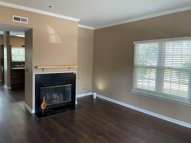 unfurnished living room featuring ornamental molding, dark wood-type flooring, and a wealth of natural light