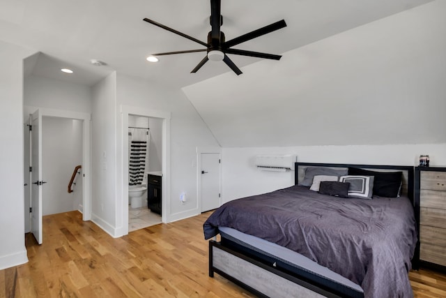 bedroom with vaulted ceiling, connected bathroom, light wood-type flooring, and ceiling fan