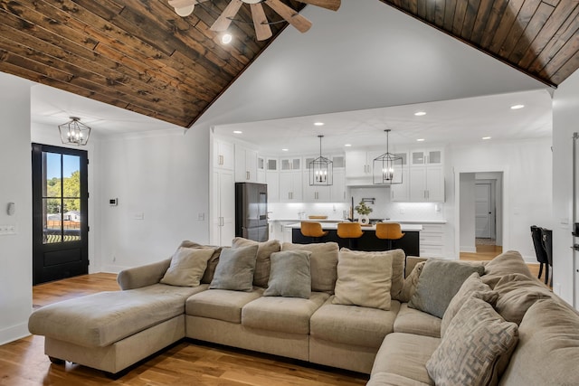 living room with ceiling fan with notable chandelier, wood ceiling, high vaulted ceiling, and light hardwood / wood-style floors