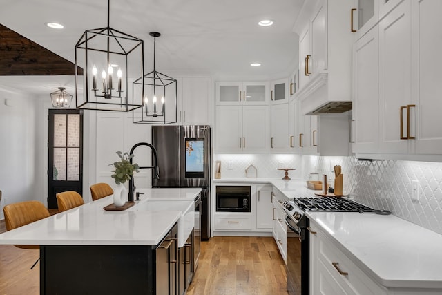 kitchen featuring a kitchen breakfast bar, a center island with sink, pendant lighting, light hardwood / wood-style flooring, and appliances with stainless steel finishes