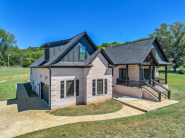 view of front of property featuring covered porch, a garage, and a front lawn