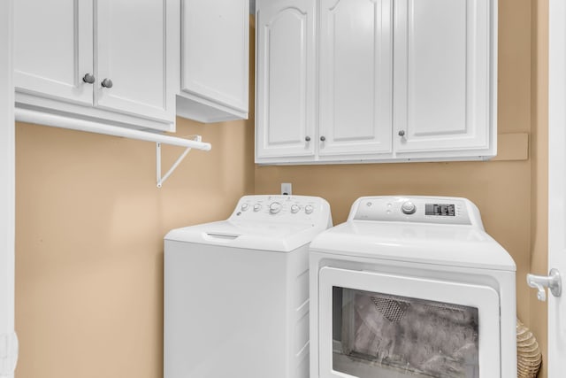 clothes washing area featuring cabinets and washer and dryer