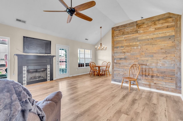 living room with vaulted ceiling, ceiling fan with notable chandelier, and wood-type flooring