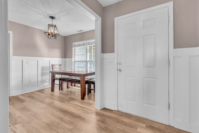 entryway featuring a textured ceiling, light hardwood / wood-style flooring, and a notable chandelier