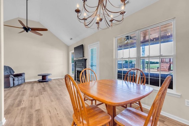 dining space with ceiling fan with notable chandelier, high vaulted ceiling, and light hardwood / wood-style flooring