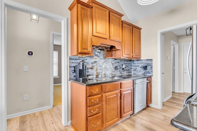 kitchen with stainless steel dishwasher, sink, lofted ceiling, light wood-type flooring, and dark stone counters