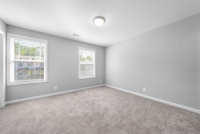 carpeted empty room with visible vents and baseboards