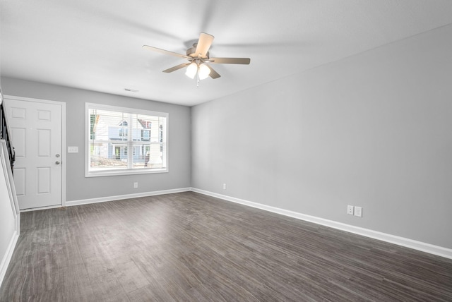 empty room with dark wood-style floors, baseboards, and ceiling fan