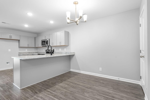 kitchen featuring visible vents, dark wood-style floors, a peninsula, appliances with stainless steel finishes, and a chandelier