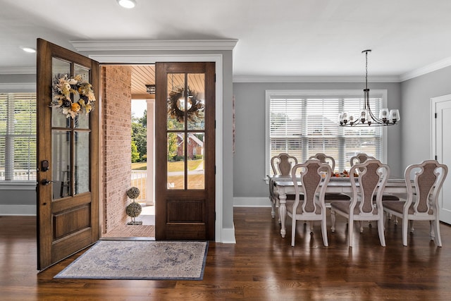 entryway with dark wood-type flooring, ornamental molding, and an inviting chandelier