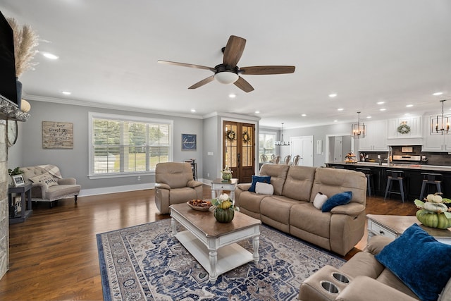 living room featuring crown molding, sink, ceiling fan with notable chandelier, and hardwood / wood-style flooring