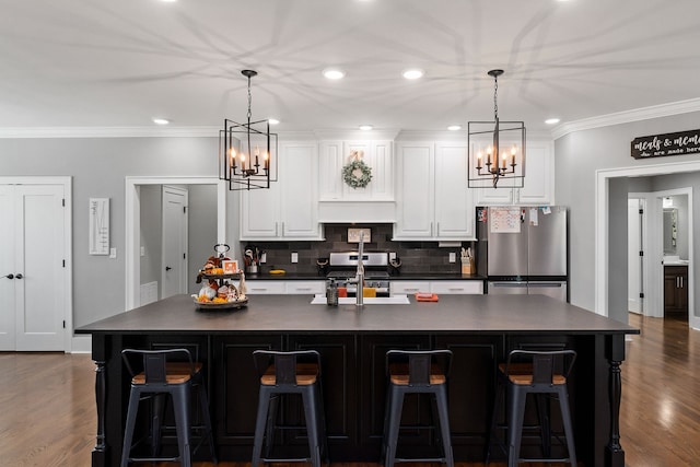 kitchen with white cabinets, stainless steel appliances, a kitchen breakfast bar, and a large island