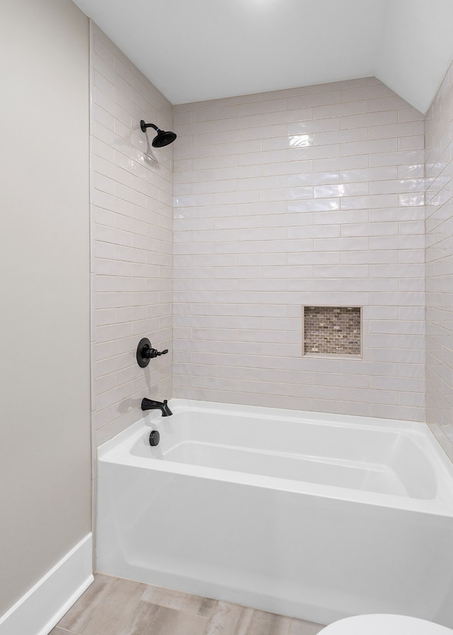 bathroom featuring tiled shower / bath, hardwood / wood-style floors, and vaulted ceiling