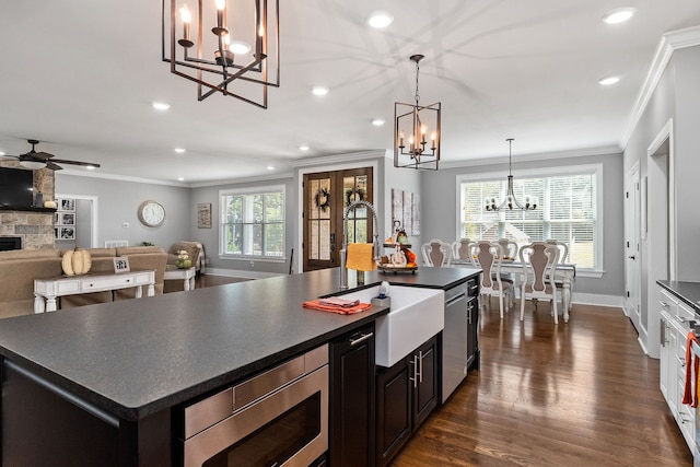 kitchen featuring a center island, ceiling fan with notable chandelier, sink, dark hardwood / wood-style floors, and a stone fireplace