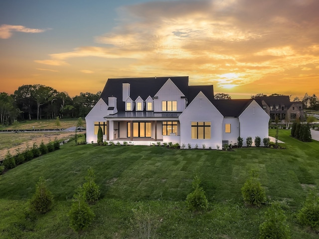 back house at dusk with a lawn