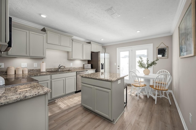 kitchen featuring a textured ceiling, a kitchen island, stone counters, and light hardwood / wood-style floors