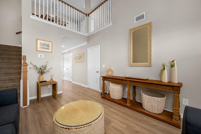 entrance foyer with a high ceiling, ornamental molding, and light hardwood / wood-style floors