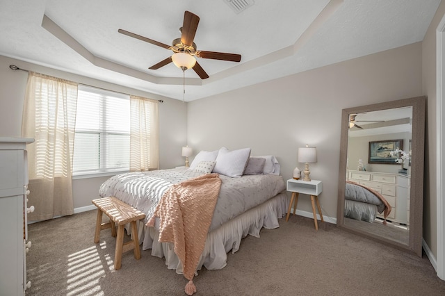 carpeted bedroom featuring a raised ceiling and ceiling fan