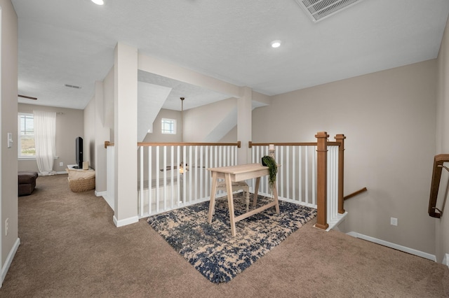 hallway with a textured ceiling and carpet floors