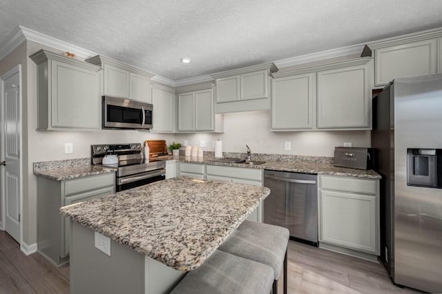 kitchen featuring a textured ceiling, a kitchen island, light wood-type flooring, and appliances with stainless steel finishes