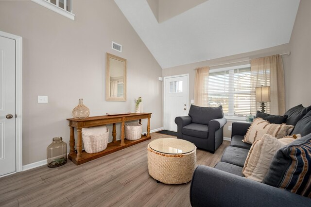 living room with high vaulted ceiling and light hardwood / wood-style flooring