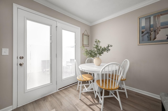 dining room with crown molding and light hardwood / wood-style flooring