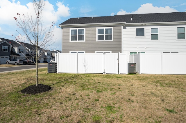 rear view of property with a yard and central AC unit